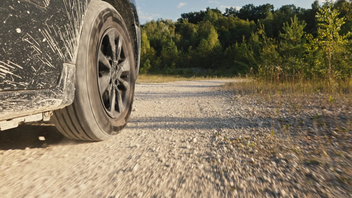 Close Up Of A Car Driving On A Dusty, Rocky Dirt Road