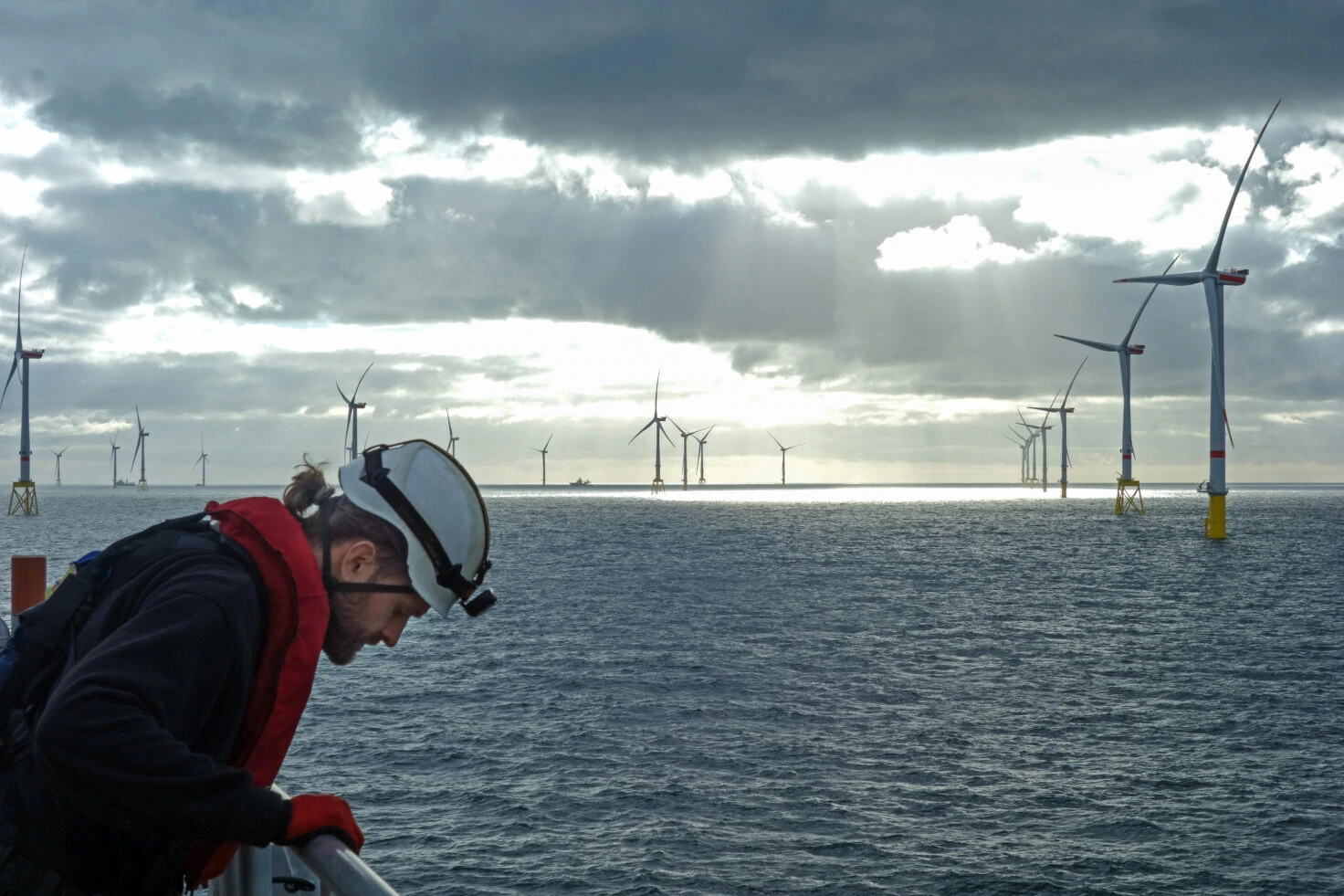 Offshore Manual Worker Looking Down From Wind Turbine With Epic Background With Sunset