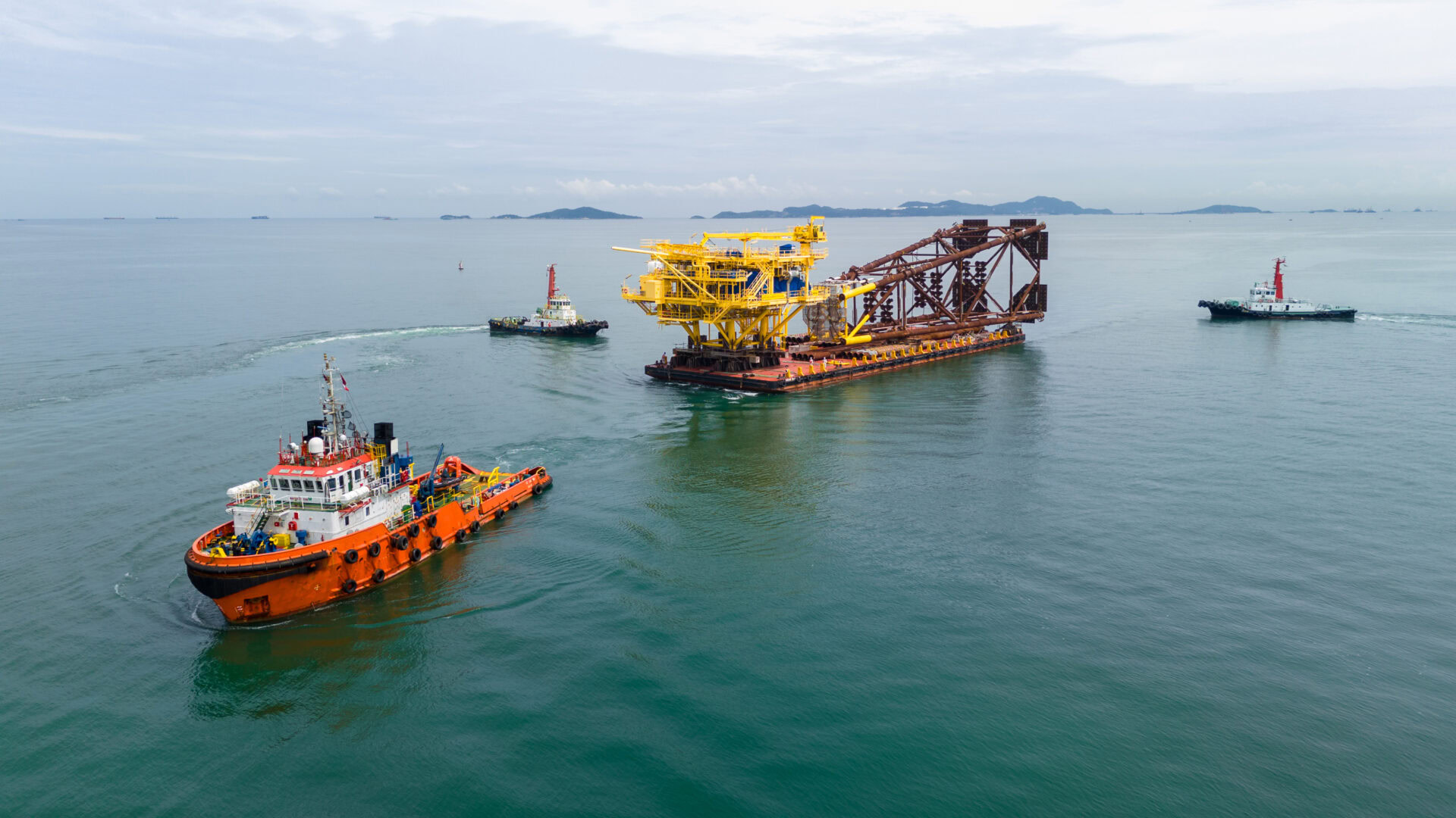 Big Construction On Ship. Tender Drilling Oil Rig On Barge Ship Transportation Rid To Oil Rig In The Middle Of The Ocean. Five Tug Boat Pulling Construction