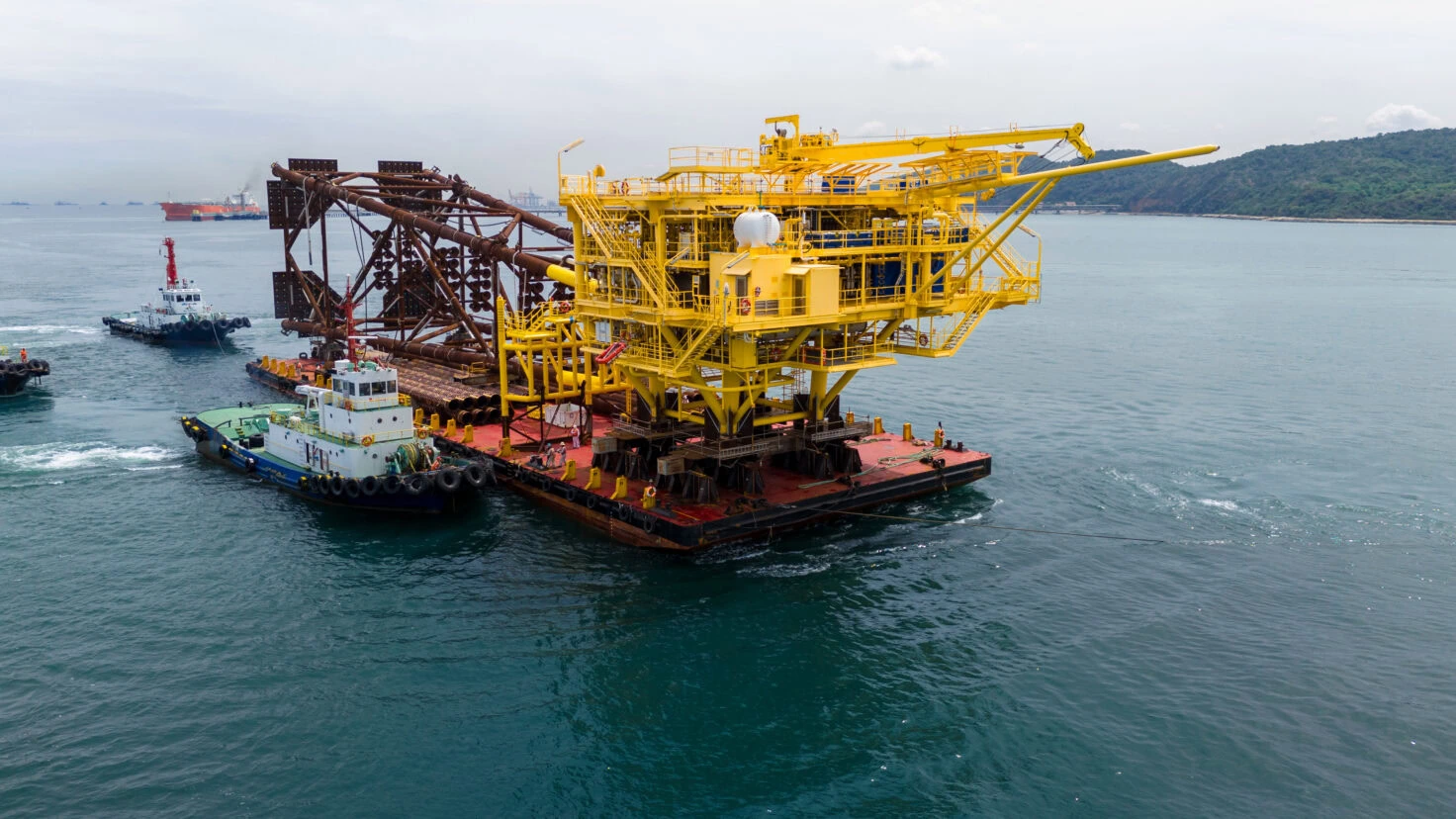 Big Construction On Ship. Tender Drilling Oil Rig On Barge Ship Transportation Rid To Oil Rig In The Middle Of The Ocean. Five Tug Boat Pulling Construction