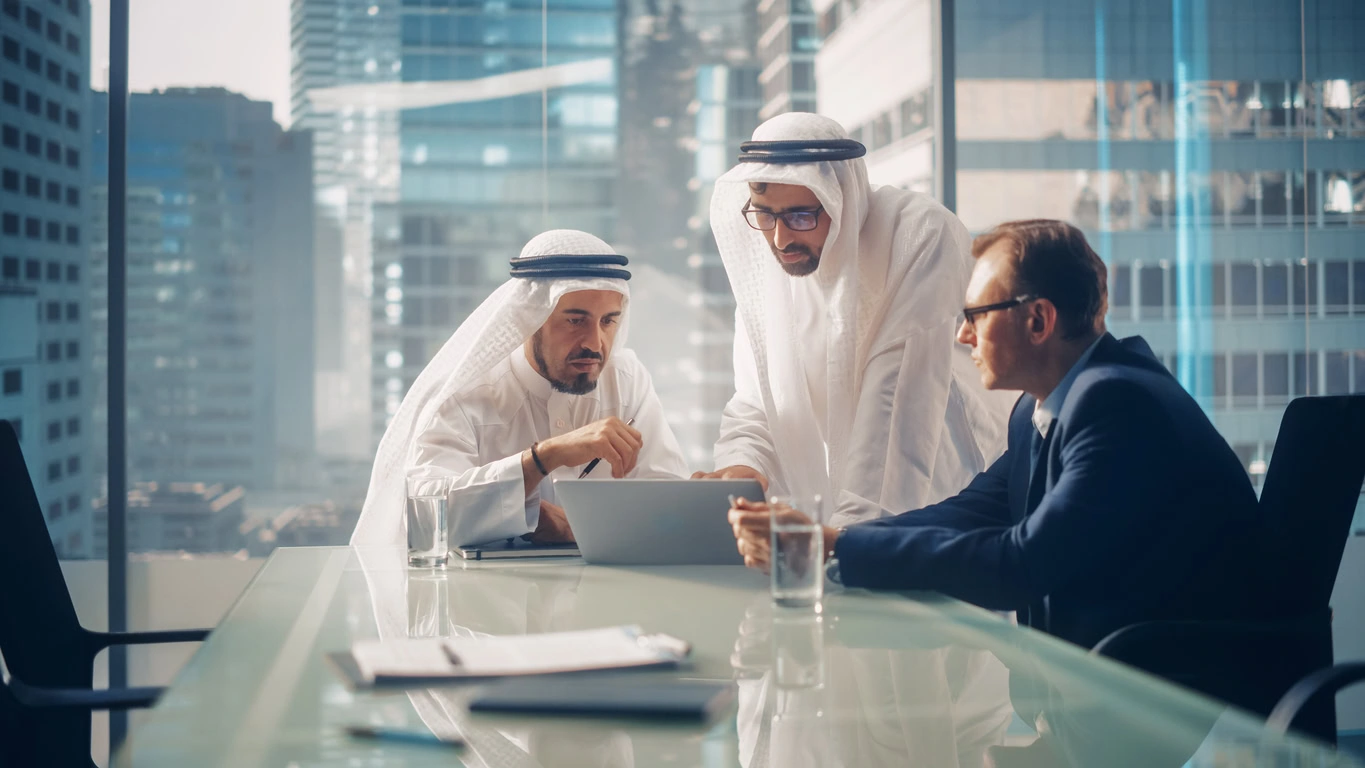 International Business Consultant Advises On Financial Strategy Plan To Successful Arab Company Owners. Multicultural Meeting In Modern Office Between American And Saudi Businessman.