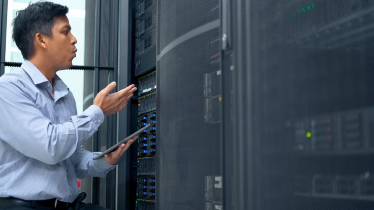System Administrator Working With Tablet In Data Center.